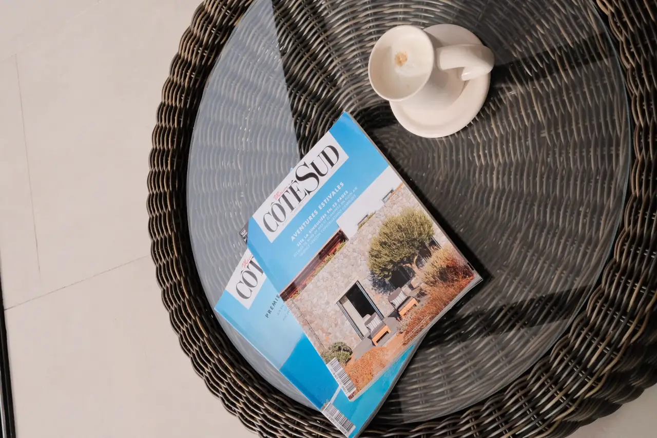 Magazines de décoration provençale posés sur une table basse en rotin